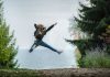 woman jumping wearing green backpack