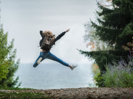 woman jumping wearing green backpack