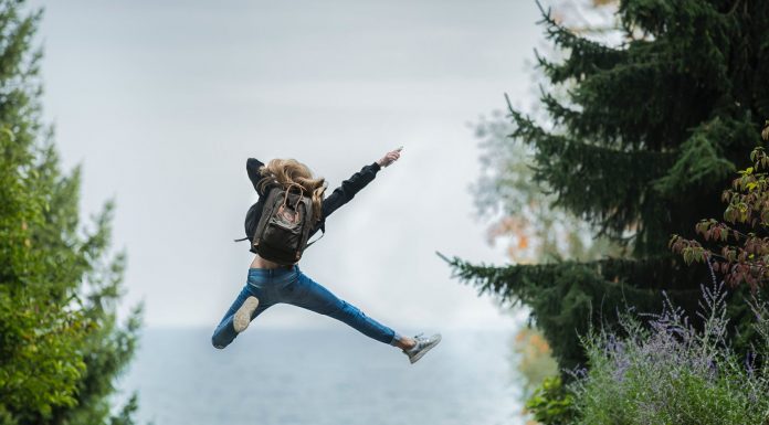 woman jumping wearing green backpack