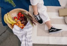 Ako rozchodiť nové topánky? person in white pants and black and white sneakers sitting on white textile