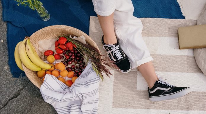 person in white pants and black and white sneakers sitting on white textile