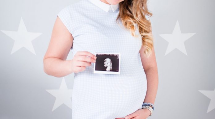 woman wearing white cap sleeved dress holding ultrasound result photo