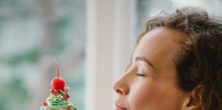 young woman enjoying aroma of cupcake