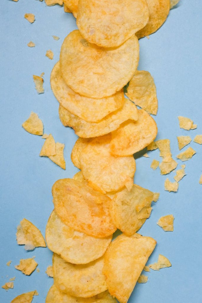 crispy chips in studio on blue surface
