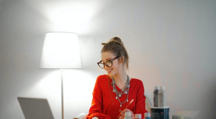 woman in red long sleeve shirt looking at her laptop