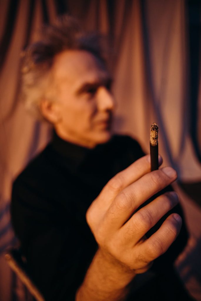man in black shirt holding cigarette stick