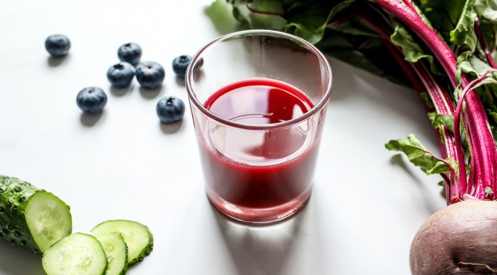 red juice in a glass beside cucumber and beetroot