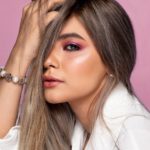 stylish model touching hair on pink background