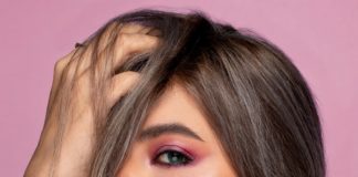 stylish model touching hair on pink background