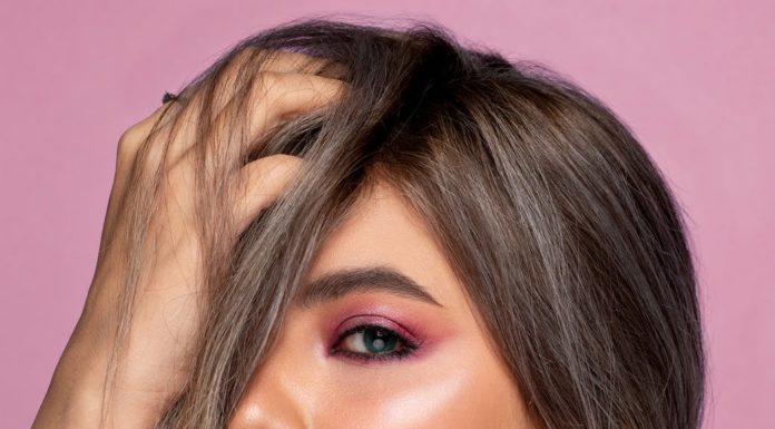 stylish model touching hair on pink background